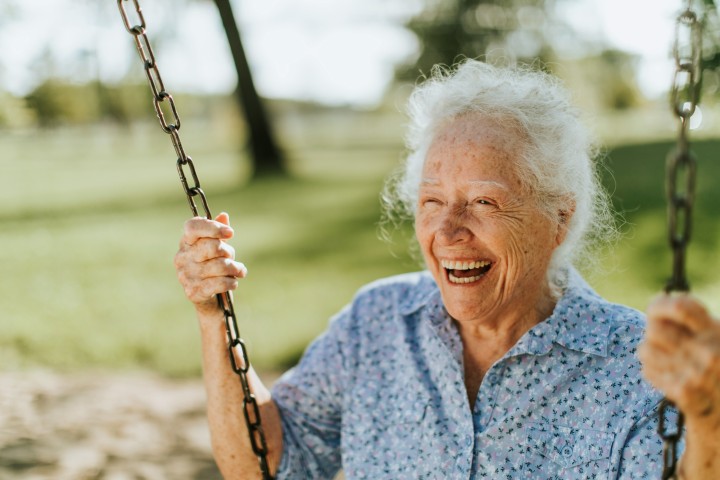 Ouder vrouw glimlachend op een schommel